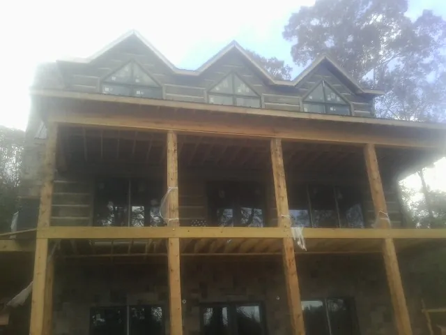 Dormers and porch framing on a large log home under construction — Roof Coating work by our crew in Olathe