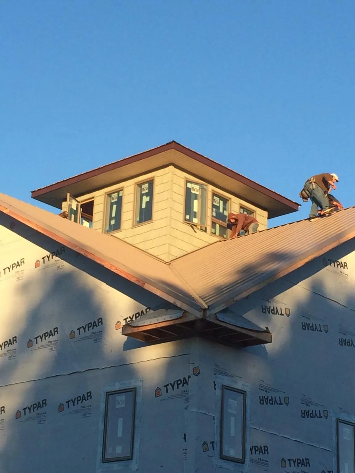 Roofers working around a rooftop cupola on a new metal roof at sunset — Roof Waterproofing in Olathe by Roofing Brothers